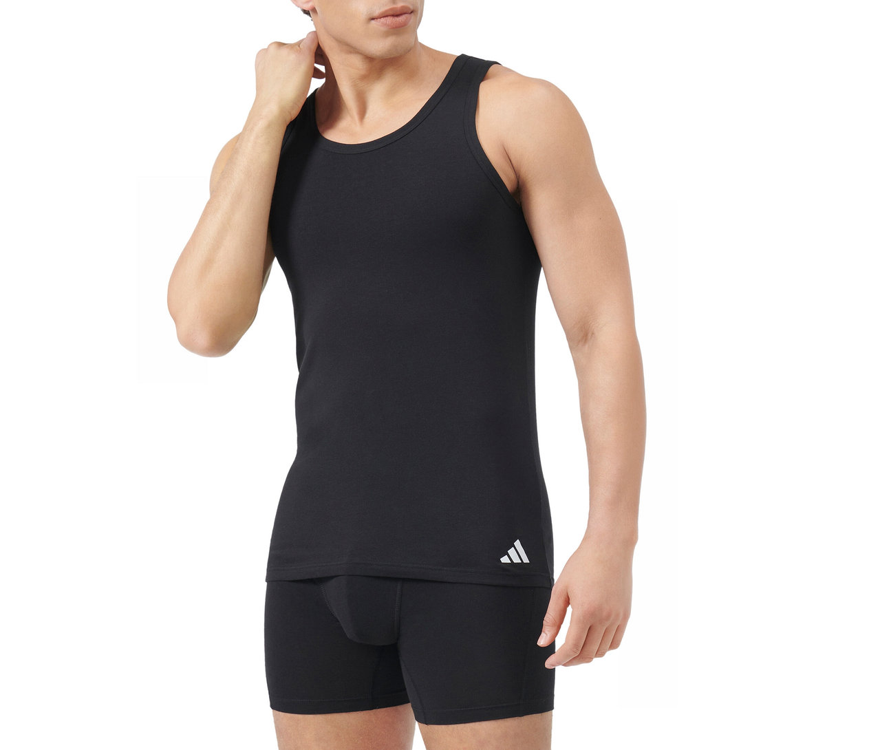 Mann in schwarzem Tanktop mit weißem Adidas-Logo und schwarzen Boxershorts, der sich am Nacken berührt, vor weißem Hintergrund.