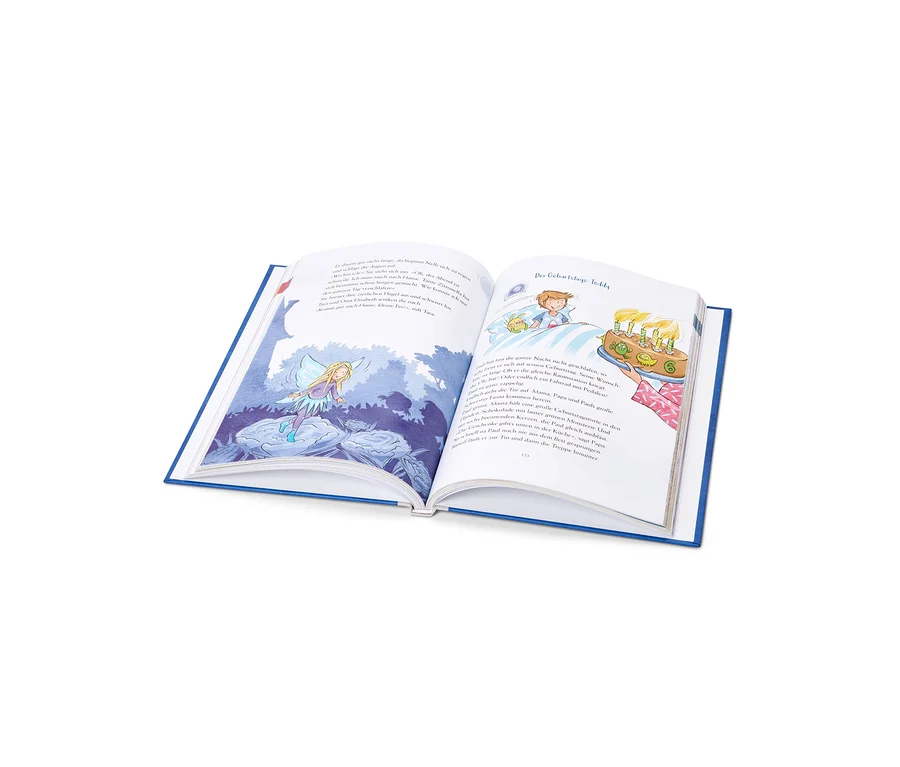 Ein aufgeschlagenes Kinderbuch mit blauem Einband liegt auf einer weißen Fläche. Die linke Seite zeigt eine Illustration einer blonden Fee mit Flügeln über blauen Blumen, die rechte Seite einen Jungen im Bett, der einen Geburtstagskuchen mit sechs brennenden Kerzen betrachtet, daneben gedruckter Text.