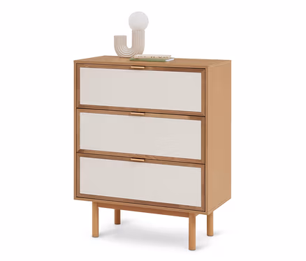 Helle Holzkommode mit drei Schubladen, die cremefarbene Stofffronten und goldene Griffe haben. Oben stehen eine moderne Lampe mit Kugel und Bücher.
