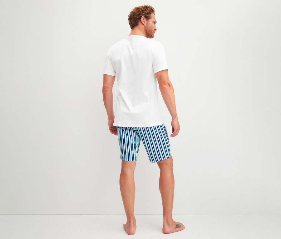 Mann von hinten, trägt ein weißes T-Shirt und ein CALIDA Herren-Shorty-Pyjama-Set mit blau-weiß gestreiften Shorts.