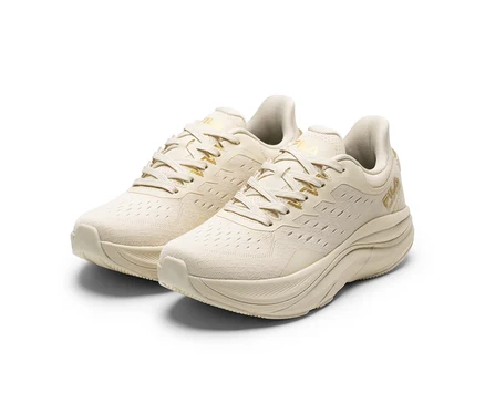Zwei cremefarbene FILA Retron Damen-Sneaker mit goldenen Akzenten und dicken Sohlen stehen auf weißem Hintergrund.