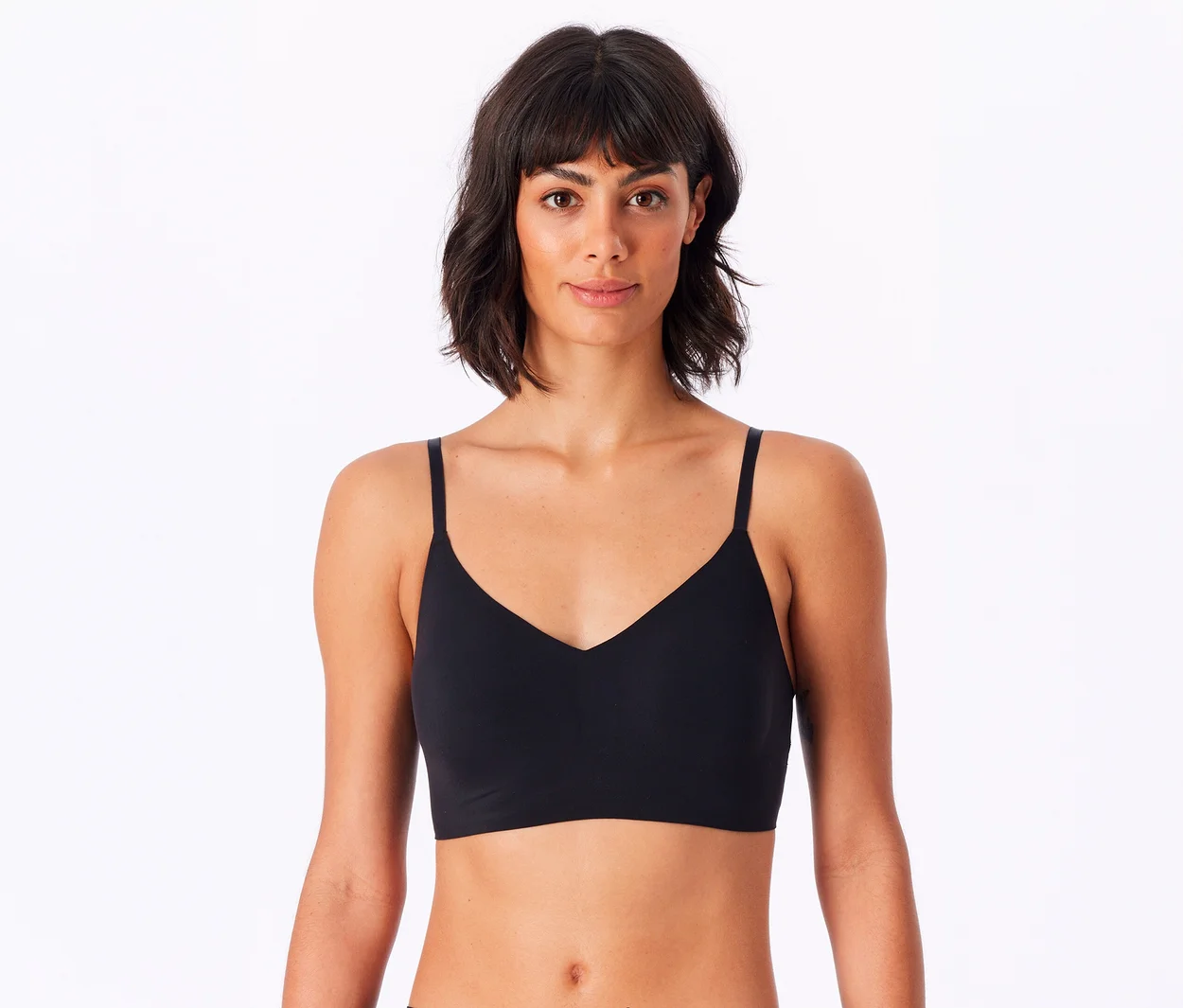 Eine Frau mit kurzen dunklen Haaren trägt ein schwarzes SCHIESSER Invisible Bustier mit Pads und blickt direkt in die Kamera.