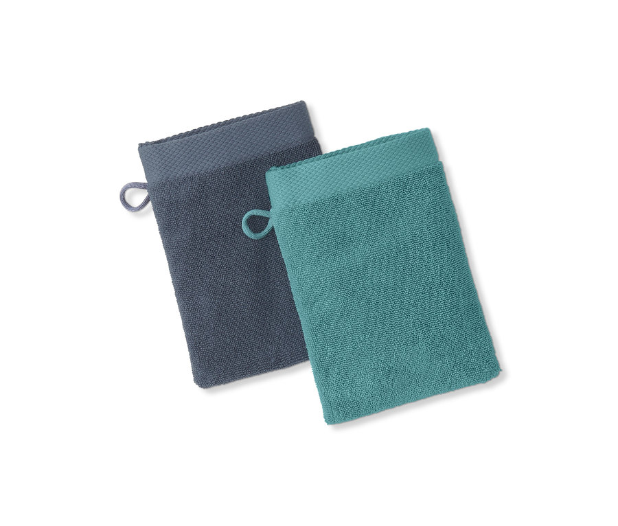 Zwei Waschlappen, einer dunkelgrau und einer türkis, liegen nebeneinander auf einem weißen Hintergrund.