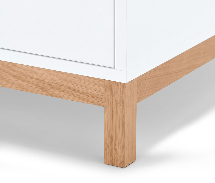 Detailansicht eines weißen Schranks mit Holzfüßen.