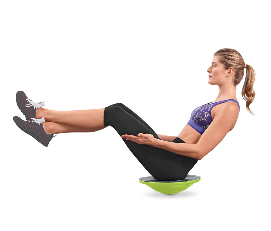 Frau sitzt auf einem Balance-Board und trainiert.