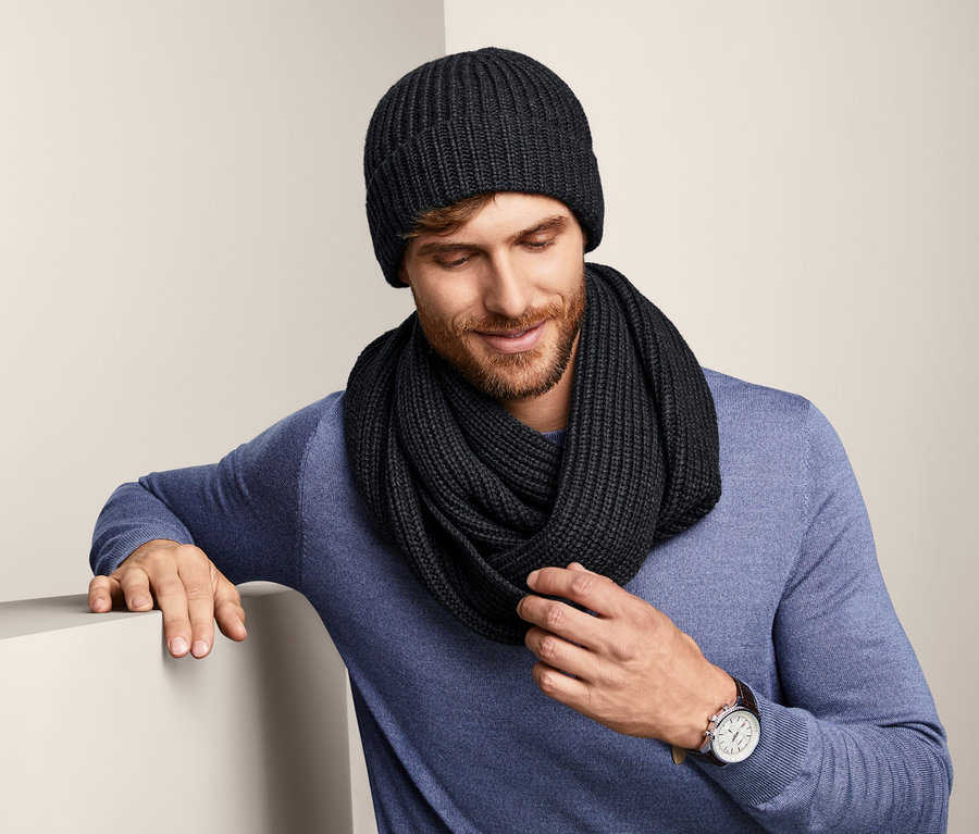 Mann mit Strickmütze und Schal schaut nach unten.