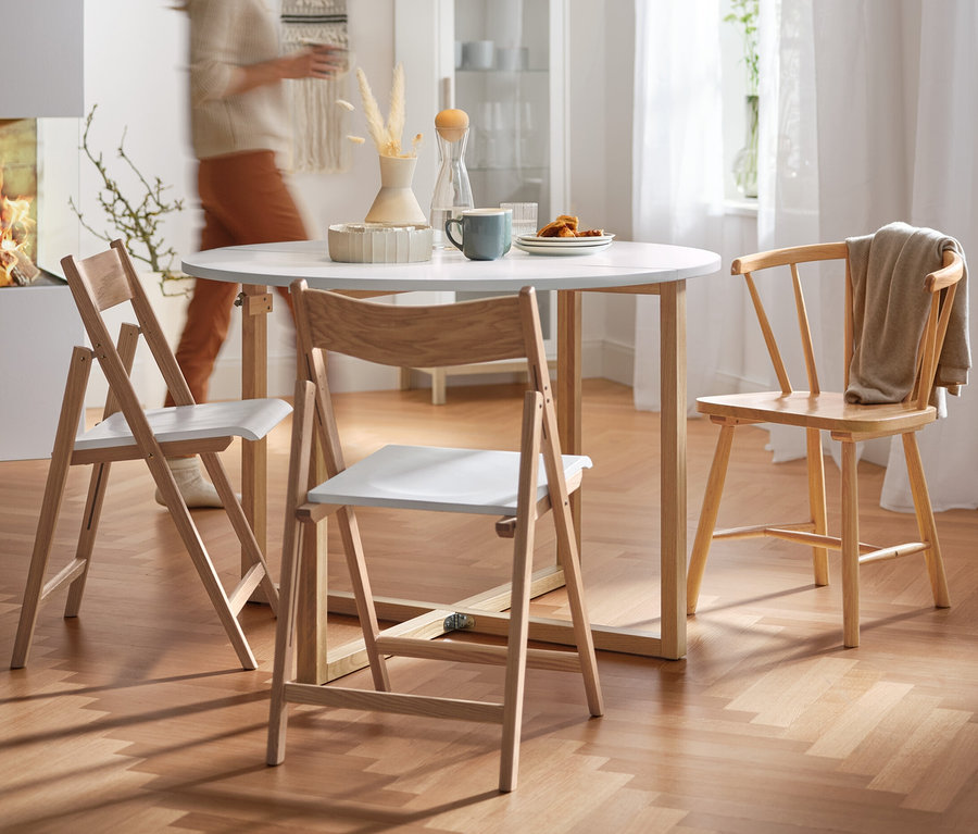 Eine Frau geht an einem runden Klappbarer Esstisch mit vier Stühlen vorbei.