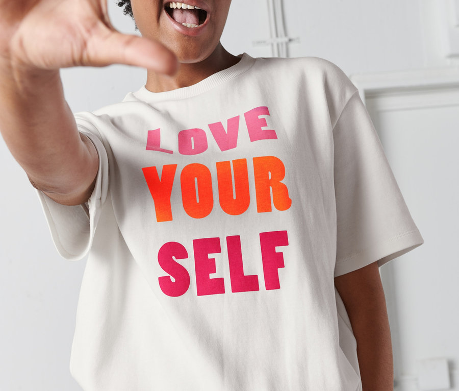 Frau trägt ein T-Shirt mit Statement-Print mit dem Aufdruck "LOVE YOUR SELF".