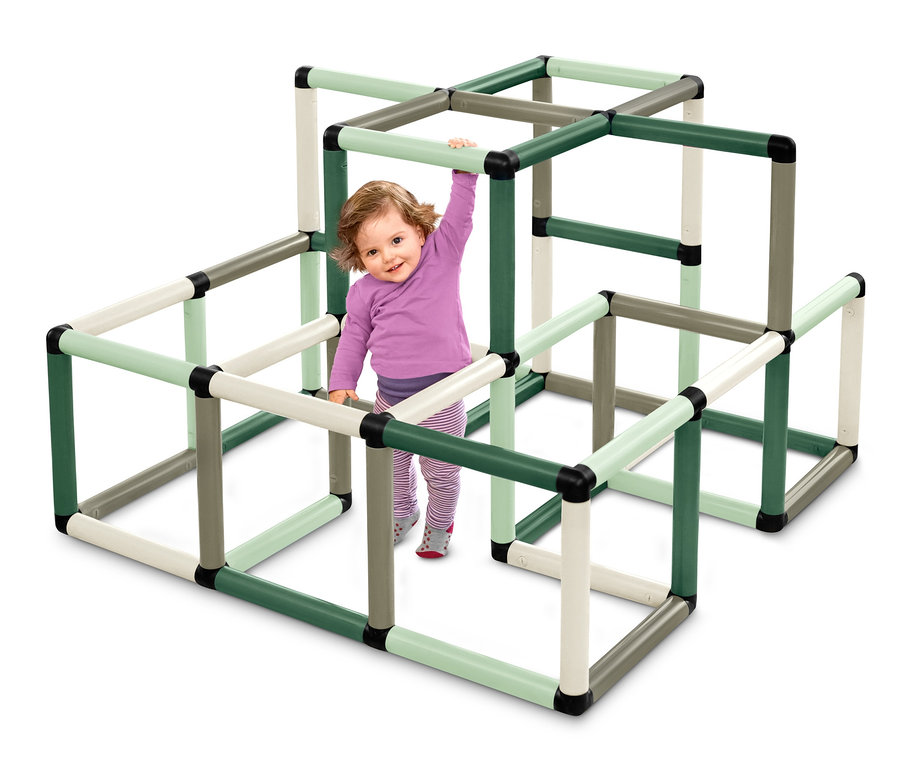 Ein Mädchen spielt auf der Quadro-Home-KLETTERPYRAMIDE und klettert auf der grünen, grauen und cremefarbenen Röhrenkonstruktion.