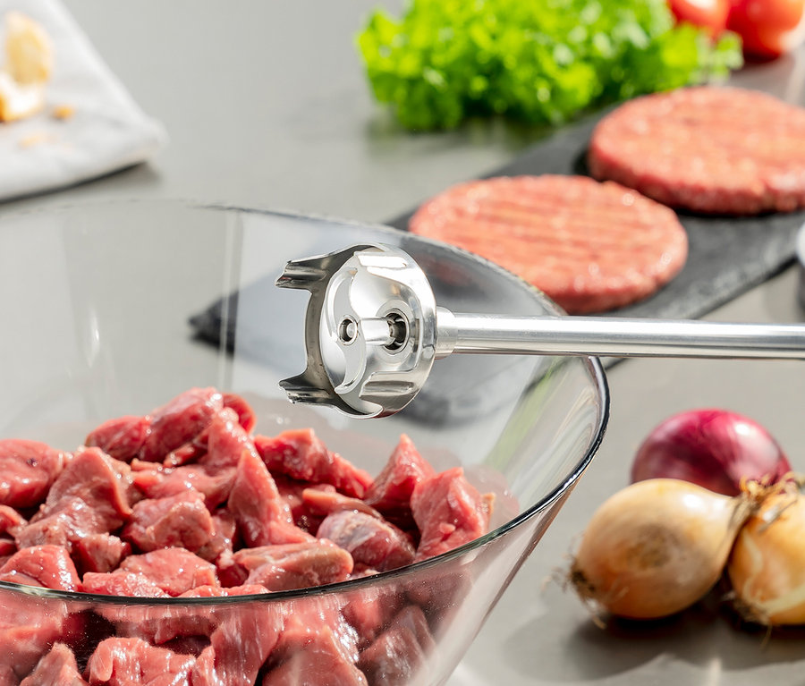 CASO Stabmixer »HB 2400 Pro XL« im Einsatz in einer Schüssel mit Fleischstücken. Im Hintergrund Burger, Zwiebeln und Salat.