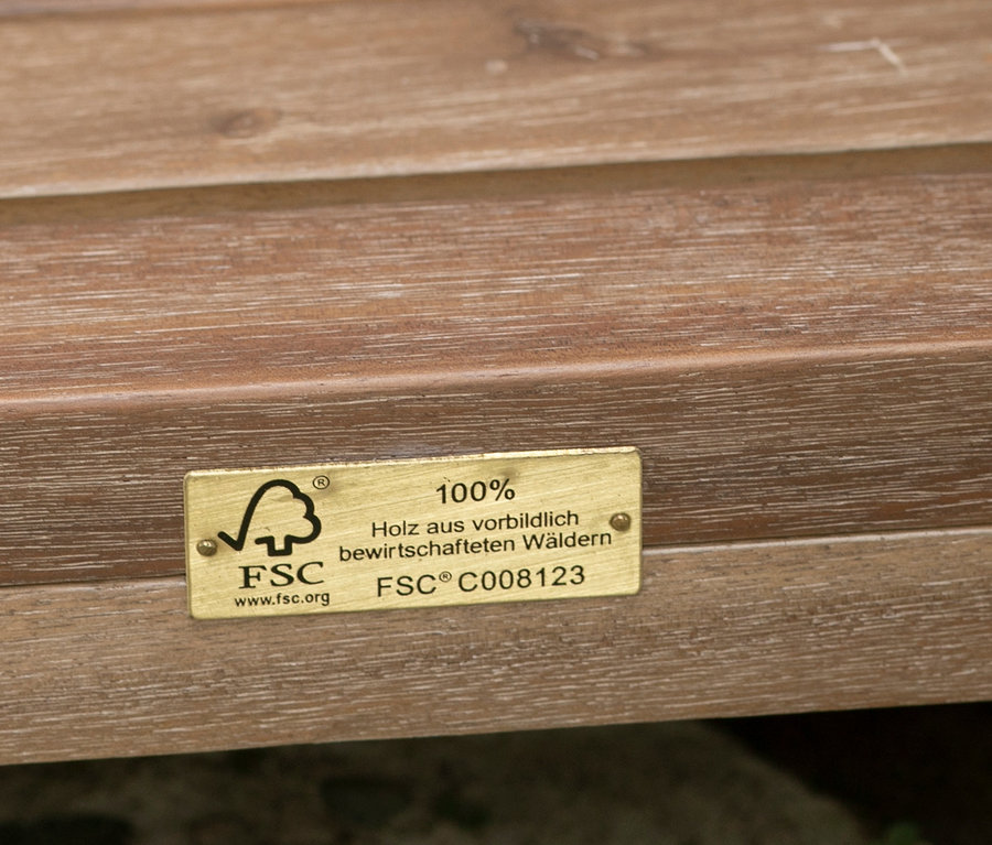 Detailaufnahme von braunem Holz mit einer goldenen FSC-Plakette.