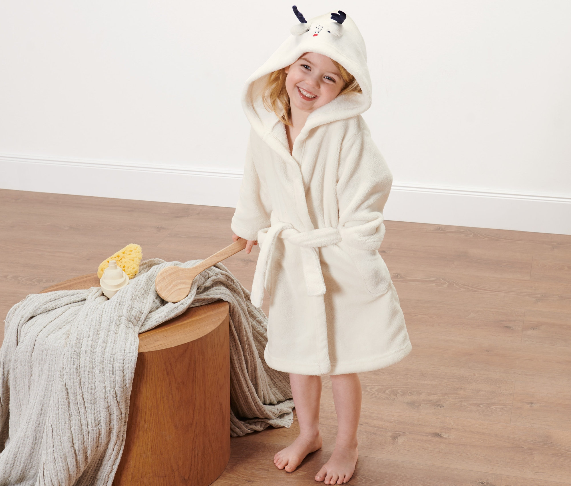 Ein Mädchen trägt einen Kleinkind-Bademantel mit Kapuze.