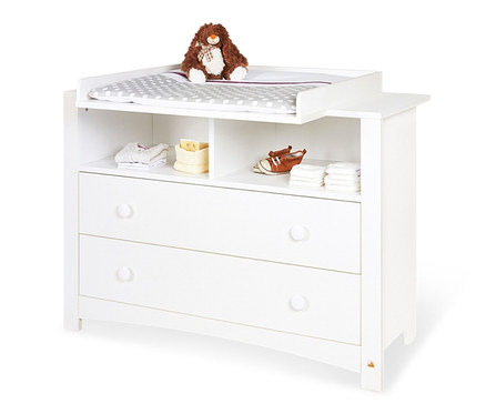 Eine weiße Wickelkommode mit einem braunen Stofftier-Teddy oben drauf und Babyschuhen, Kleidung und Windeln im offenen Regal.