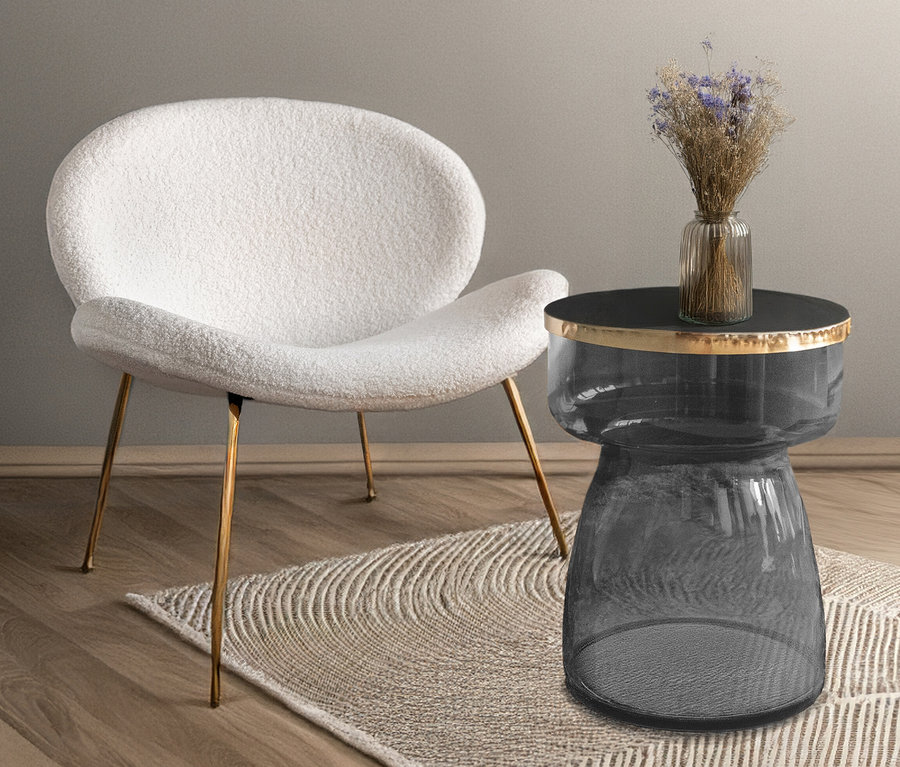 Ein weißer Kayoom Janne Stuhl und ein gläserner Beistelltisch mit einer Vase auf einem beige Teppich.