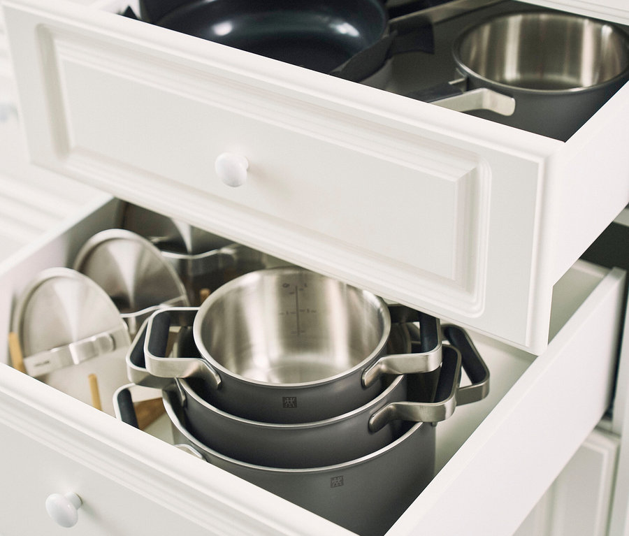 Geöffnete Schubladen einer weißen Küchenzeile gefüllt mit Kochtöpfen und Pfannen. ZWILLING PURE Edelstahl-Kochgeschirr-Set, 5-teilig, grau, ist sichtbar.
