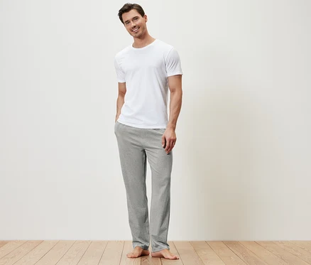 Mann trägt ein weißes T-Shirt und eine graue Relaxhose.