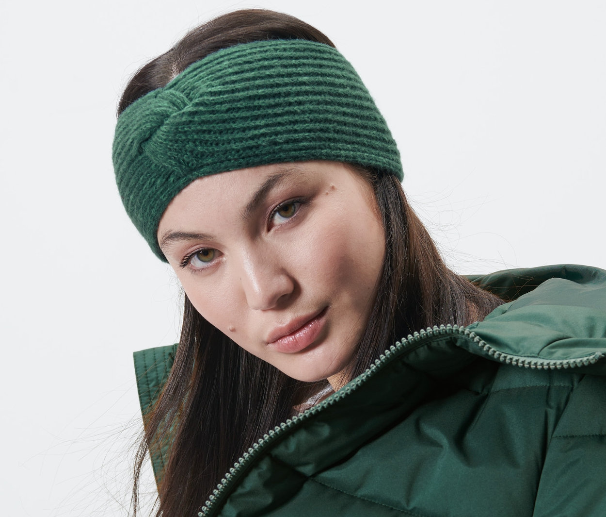 Frau trägt ein dunkelgrünes Strick-Stirnband und eine grüne Jacke.
