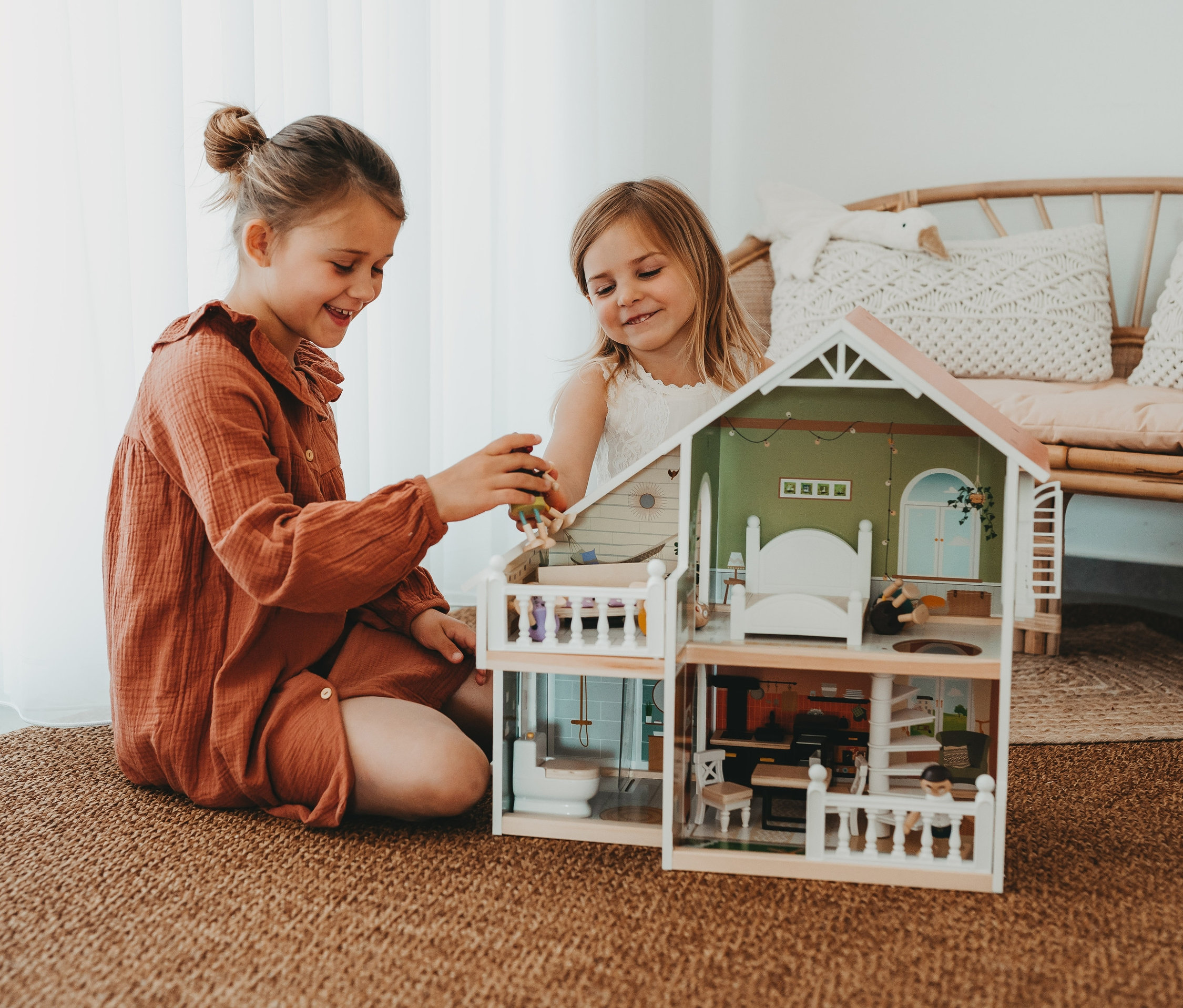 Zwei Mädchen spielen mit einem small foot Puppenhaus mit Dachterrasse.