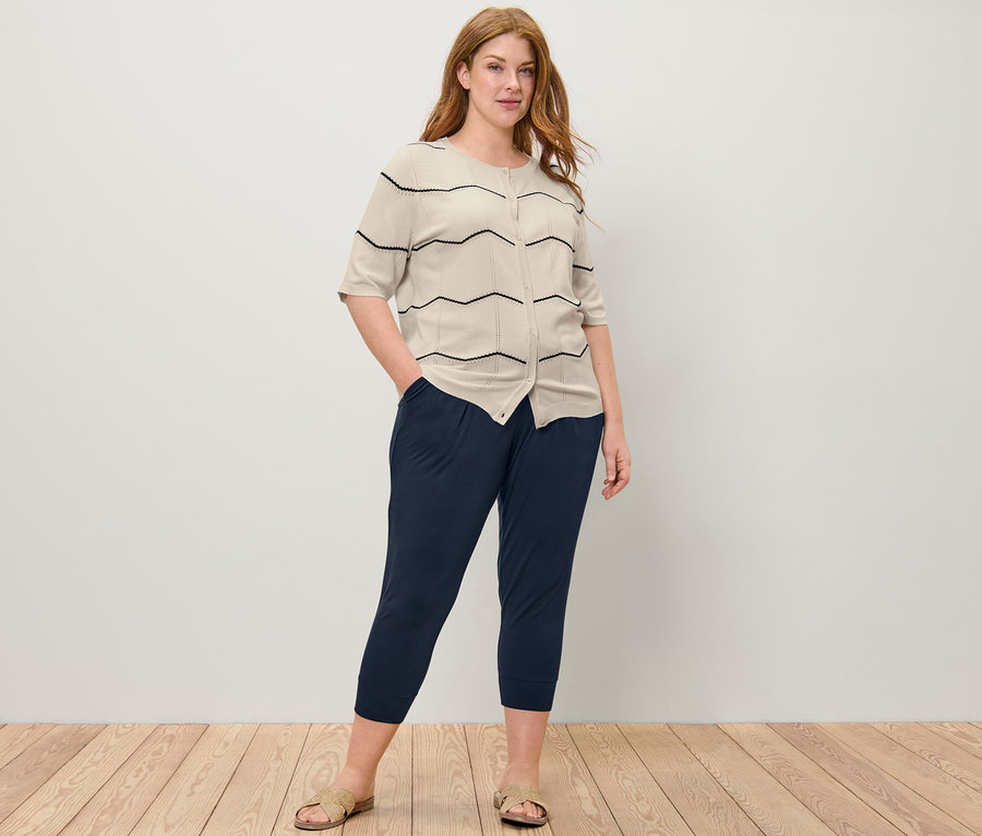 Frau posiert in Feinstrick-Cardigan mit Ajour-Muster und 3/4-Jerseyhose.