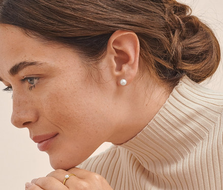 Frau trägt Ohrstecker, 925 Silber rhodiniert, mit Süßwasserzuchtperlen und zarten Ring mit Süßwasserzuchtperle.