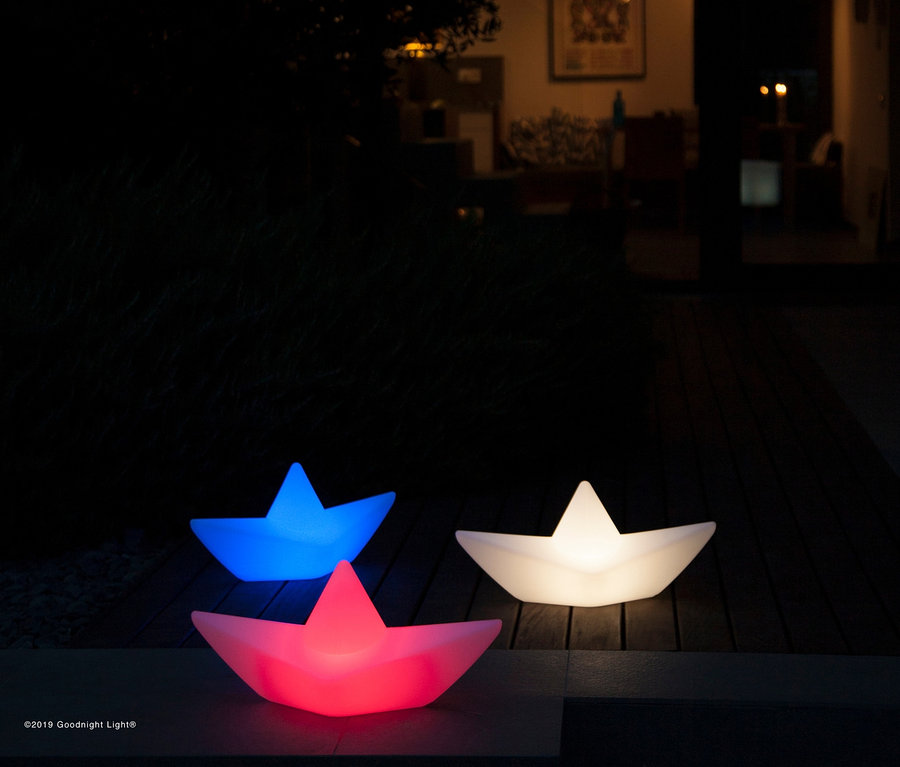 Beleuchtete Goodnight Light LED-Leuchte »Boot« in Rot, Blau und Weiß auf einem Holzboden im Freien bei Nacht.