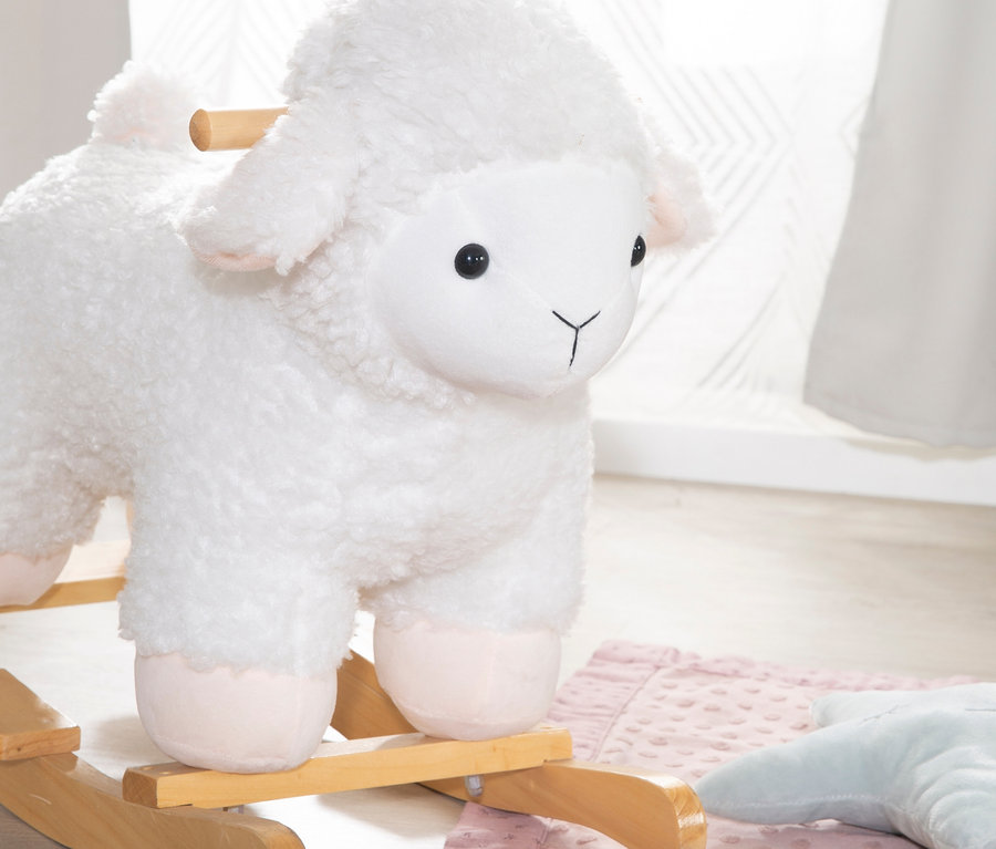 Das roba Schaukeltier Schaf steht auf einem Holzboden neben einer rosa Decke.