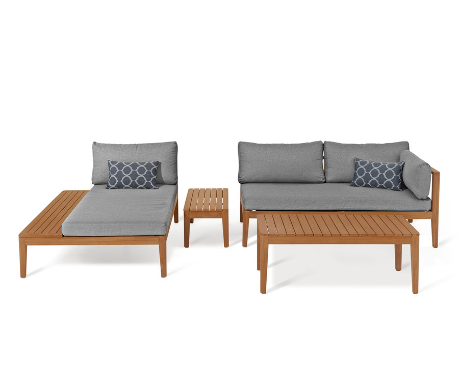 Teak-Lounge-Ecke mit grauen Kissen und zwei Teakholztischen.