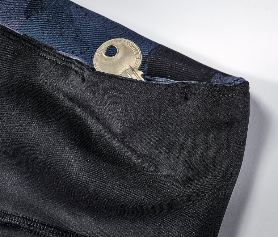 Detail einer Wende-Sporttight in Schwarz und Navy mit einem Schlüssel in der Tasche.