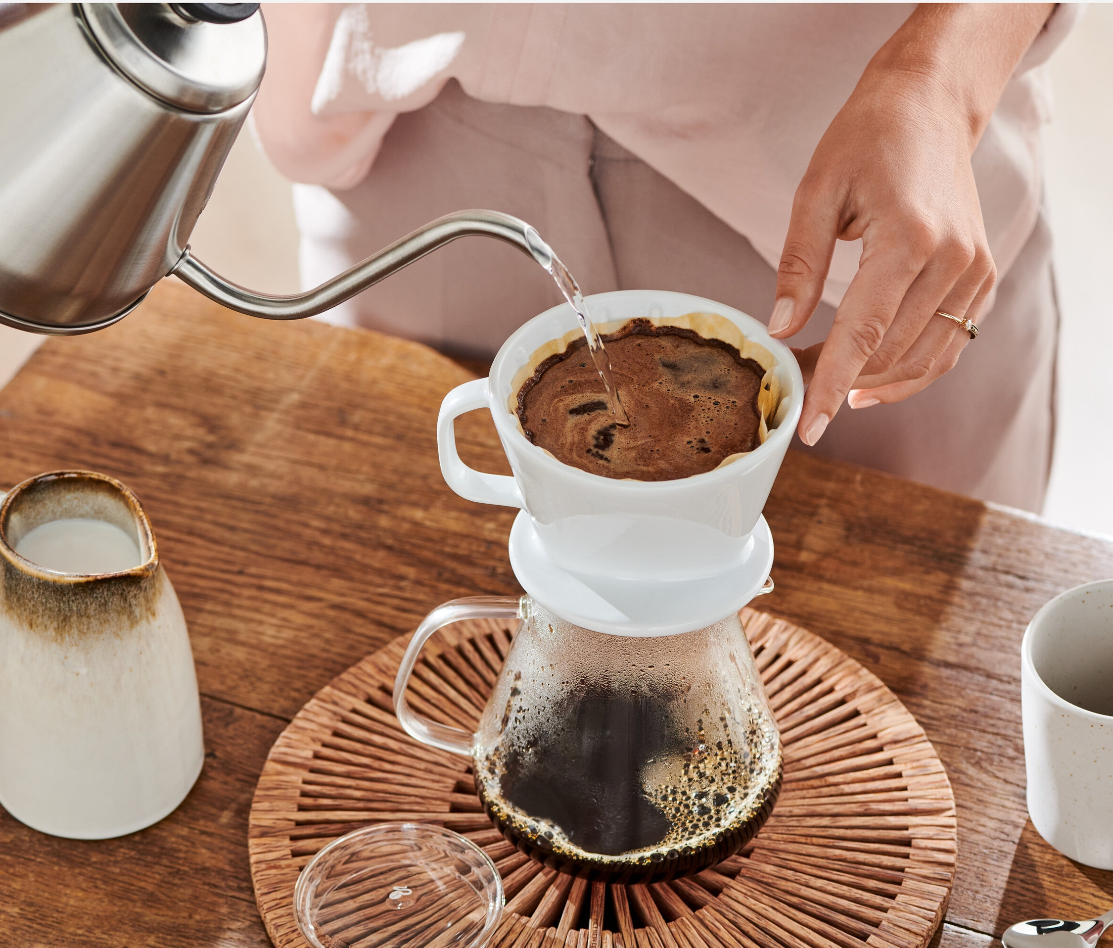 Frau gießt Wasser aus einem Kessel in einen weißen Kaffee Handfilter Gr. 2 mit Filterpapier Gr. 2, weiß, 18x 80 Stk.