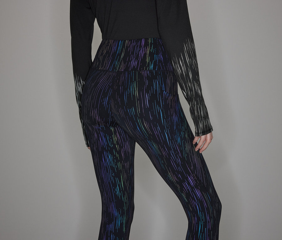 Person trägt ein schwarzes Langarmshirt und glänzende Leggings.