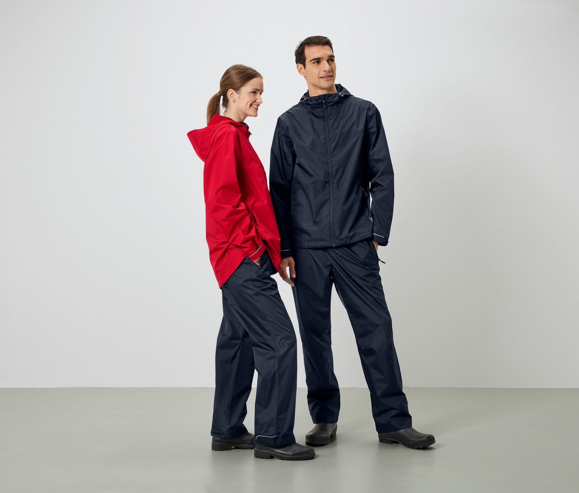 Ein Mann und eine Frau stehen nebeneinander und tragen Regenjacken und Regenhosen.