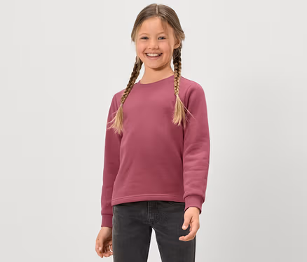 Lächelndes Mädchen mit Zöpfen in einem rosa Kinder-Sweatshirt mit angerauter Innenseite.