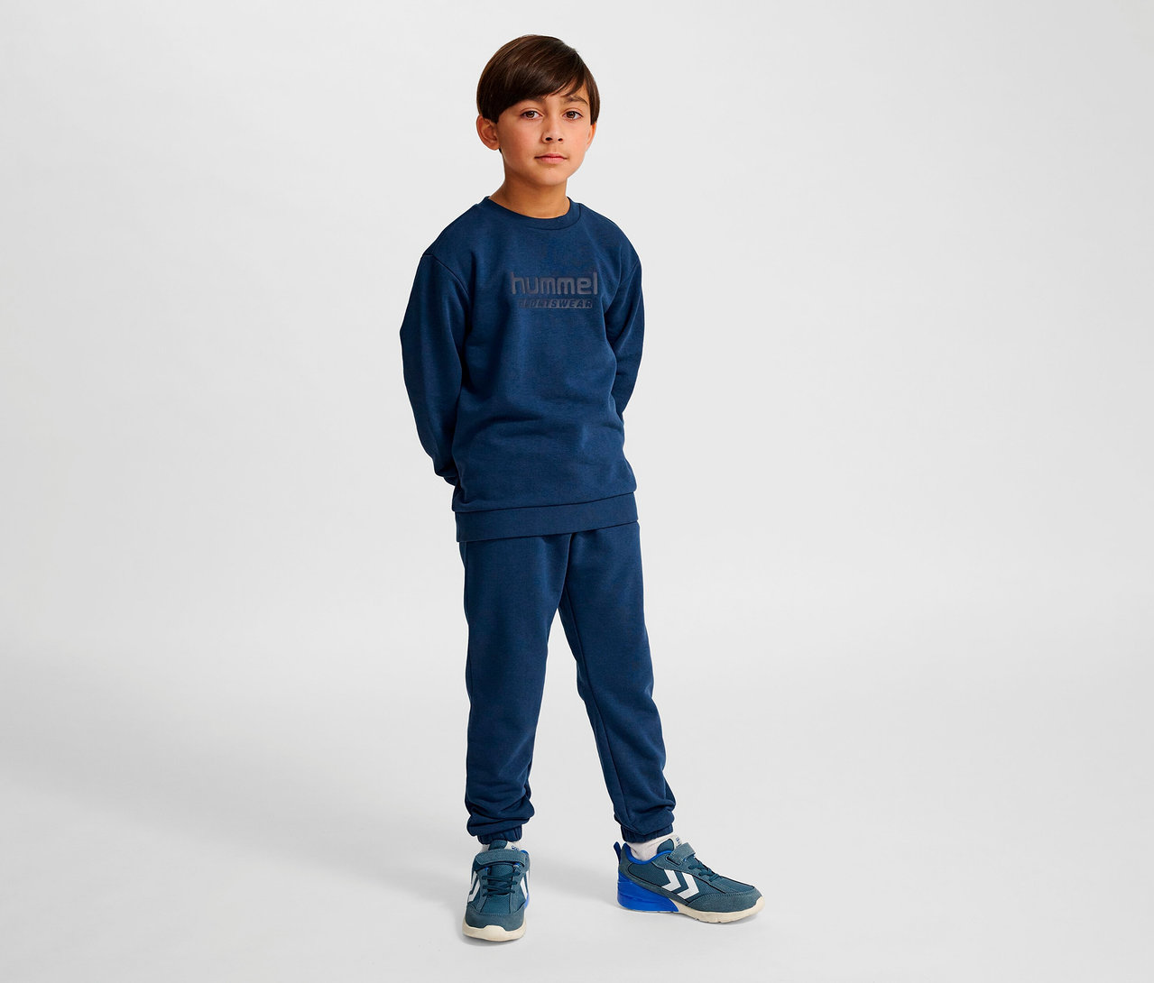 Junge steht und trägt blaues HUMMEL HMLJR Base-Sweatshirt.