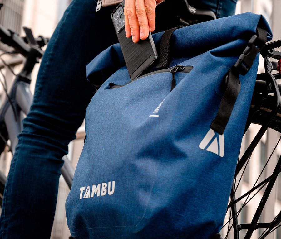 Mann auf Fahrrad legt Handy in blaue Tambu INAYA Fahrradtasche.