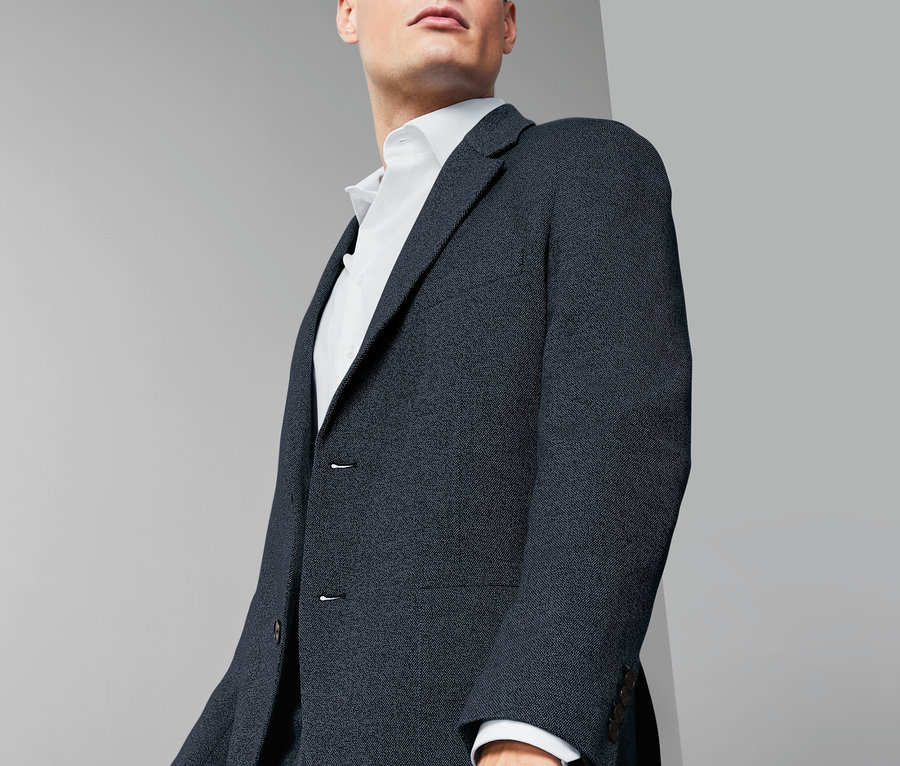 Mann trägt ein marineblaues Jersey-Sakko und ein weißes Hemd.
