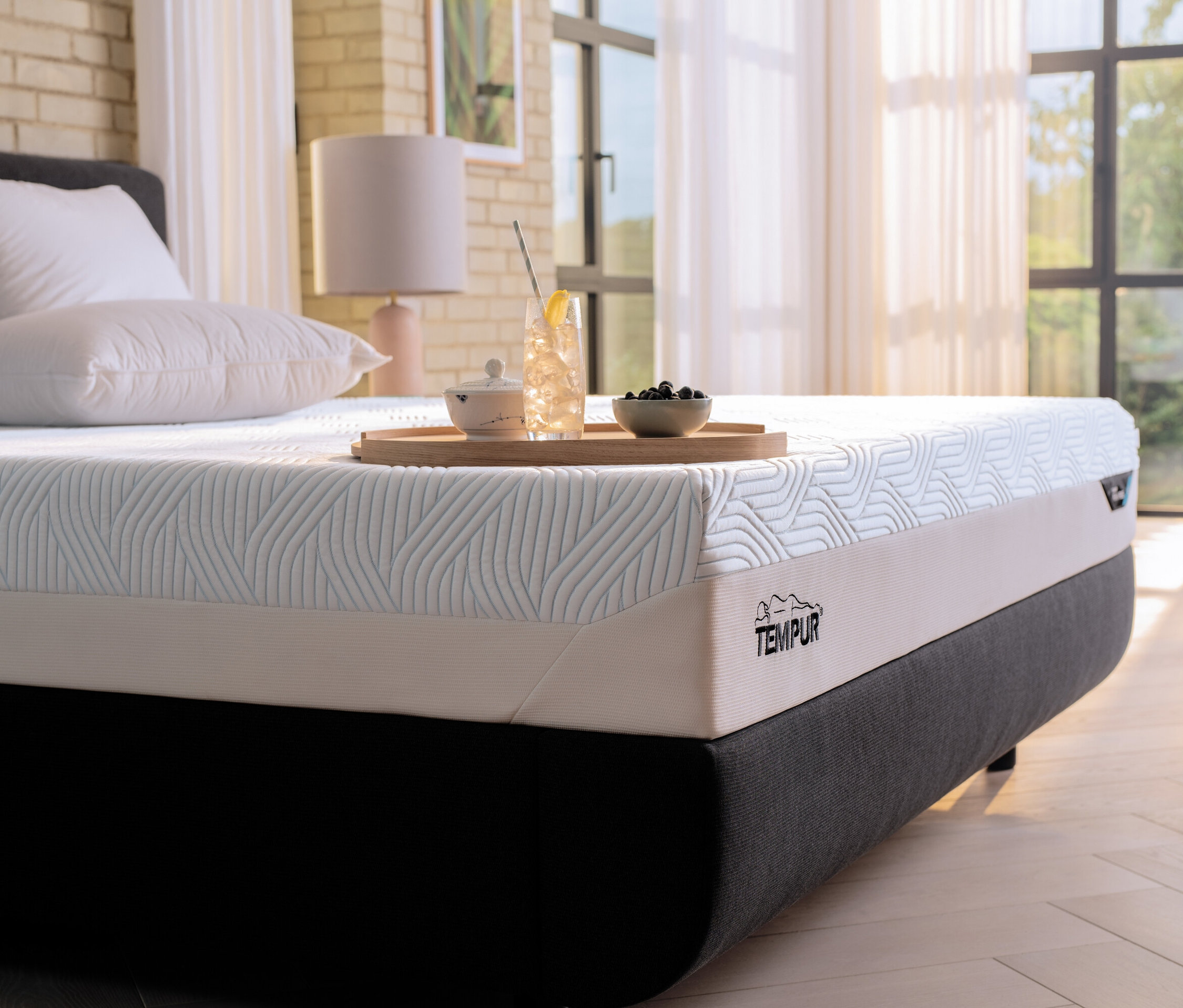 Auf einem Bett liegt eine Tempur Matratze Prima, soft. Auf der Matratze steht ein Tablett mit Getränk und Obst.