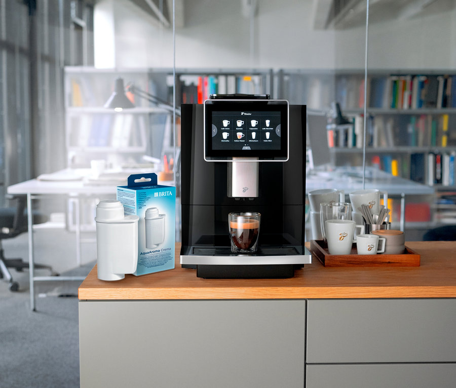 Kaffeemaschine bereitet Kaffee in einem Glas neben einem BRITA-Filter zu.