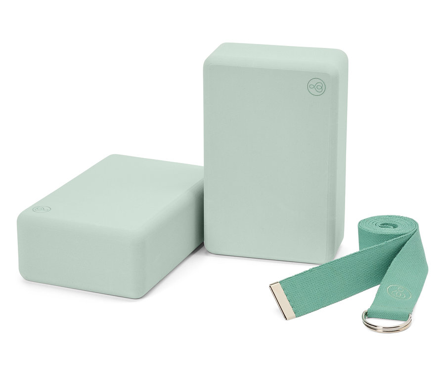 Zwei hellgrüne Yoga-Blöcke und ein passender Gurt.
