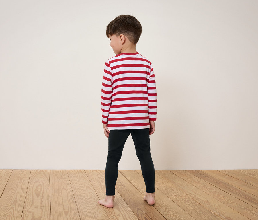 Ein Junge steht mit dem Rücken zur Kamera und trägt ein rot-weiß gestreiftes Langarmshirt und schwarze Leggings.