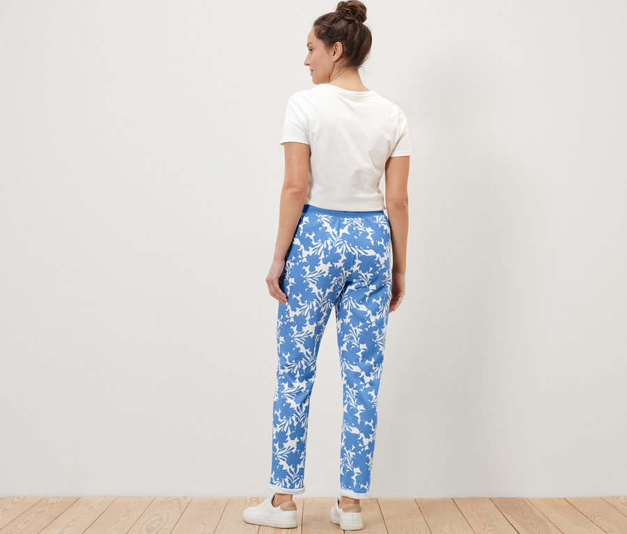 Frau steht mit dem Rücken zur Kamera und trägt eine bedruckte Sweatpants.