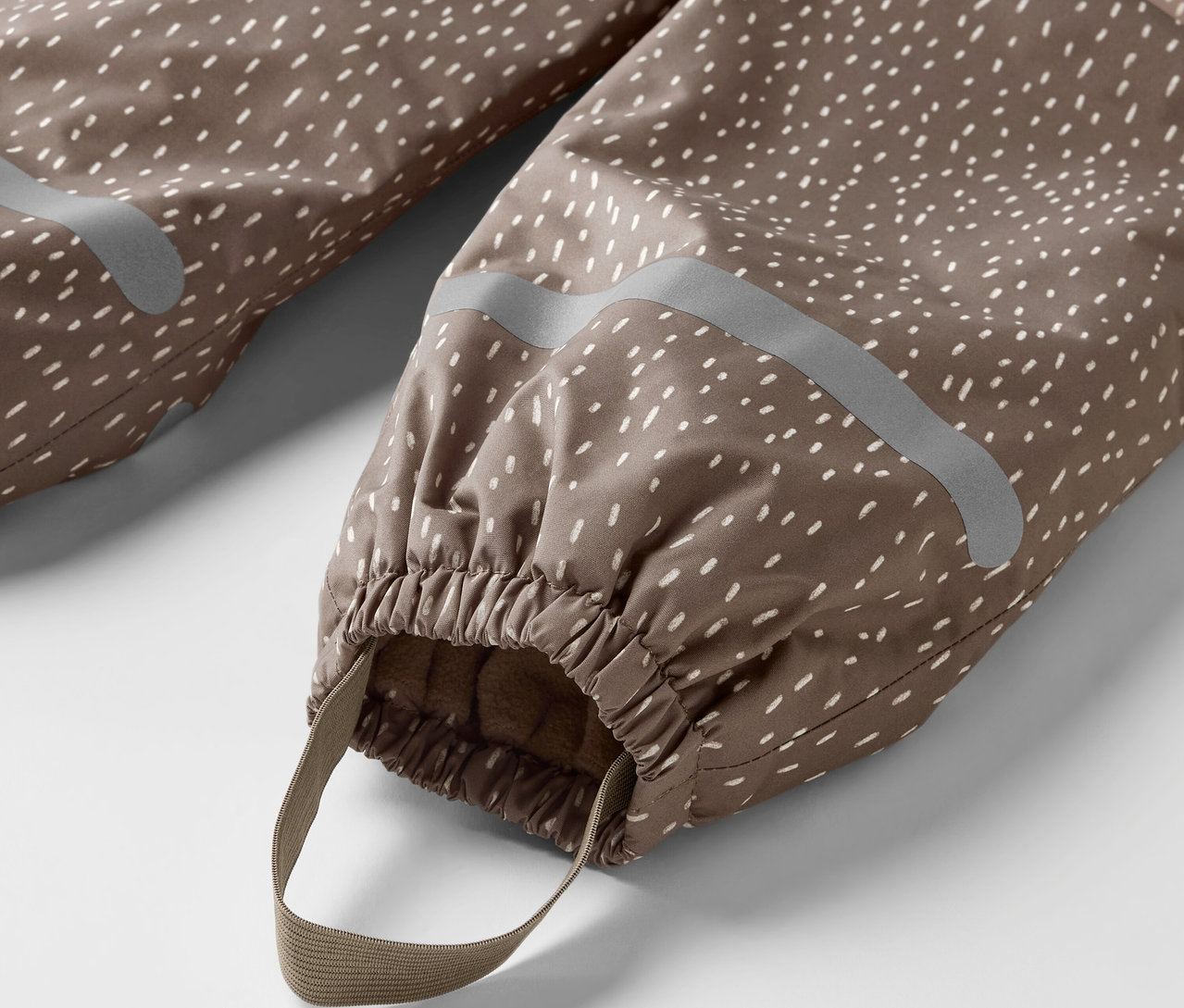 Detail einer Kinder-Thermo-Regenhose, Bär, braun mit weißen Punkten, mit Gummizug und Band.