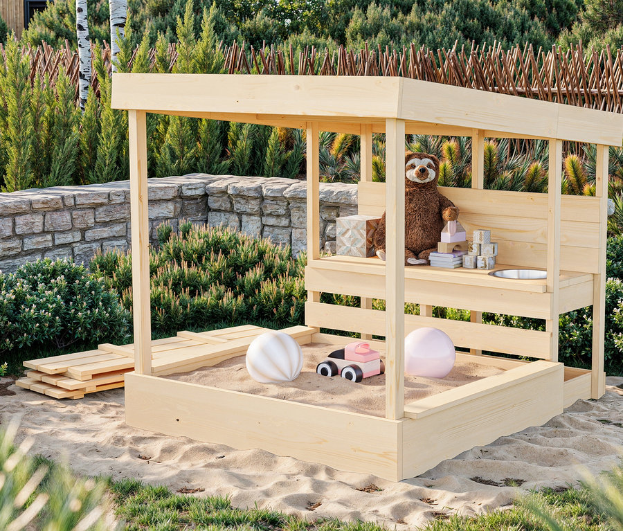 Ein hölzernes Sandhaus mit Spielzeug darin steht im Sand.