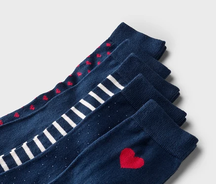 Fünf marineblaue Socken liegen übereinander, mit roten Herzen, weißen Streifen, weißen Punkten und einem einzelnen roten Herz.