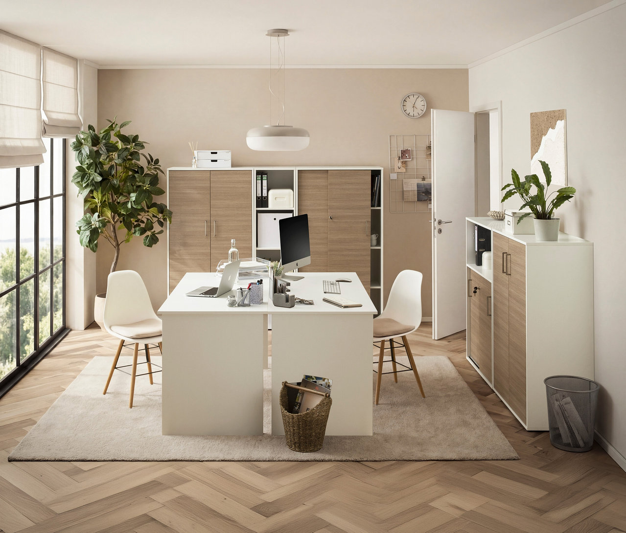 Ein Büro mit Schreibtisch, Stühlen, Computern und Regalen. Eine Zimmerpflanze steht neben dem Fenster.