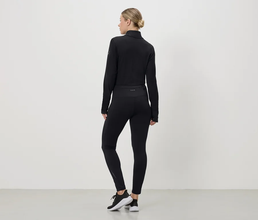 Frau von hinten in schwarzem Sportoutfit aus Oberteil, Leggings und Turnschuhen vor einem weißen Hintergrund.