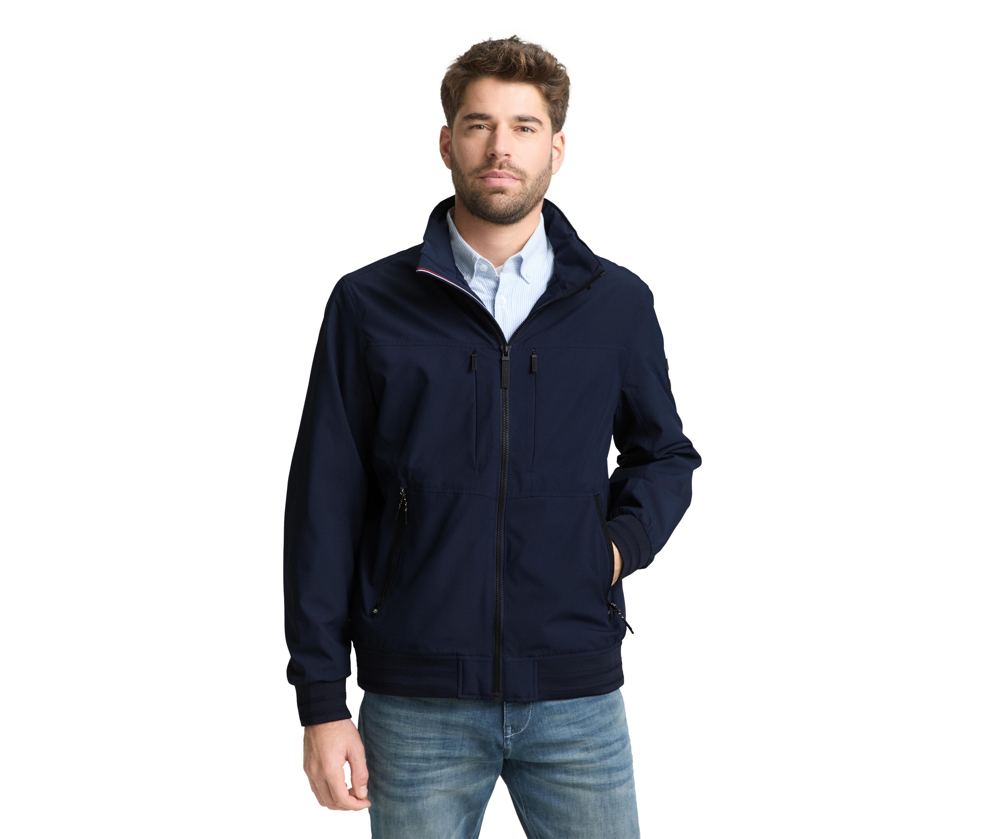 Mann mit Bart trägt eine marineblaue Jacke und Jeans.