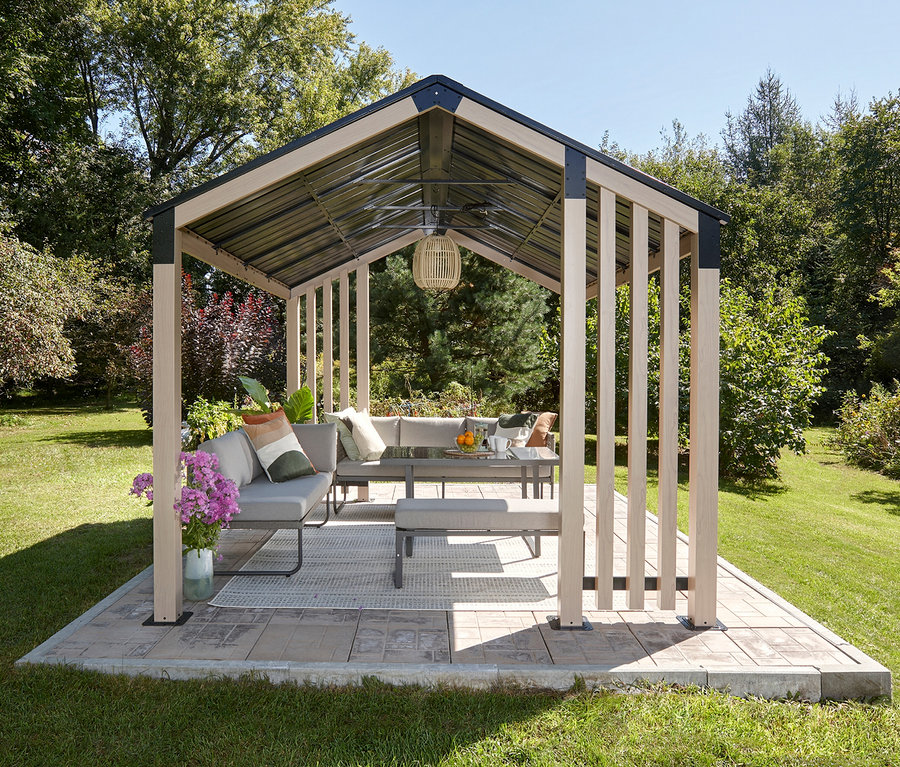 Überdachter Pavillon mit Sitzecke, Tisch und Bank auf einer Terrasse im Garten.