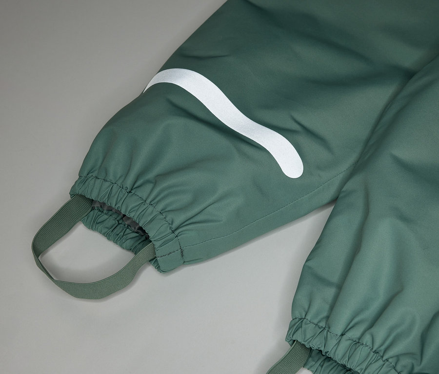 Nahaufnahme einer grünen Regenhose mit Gummizug am Knöchel und einem weißen, geschwungenen Streifen am Bein.