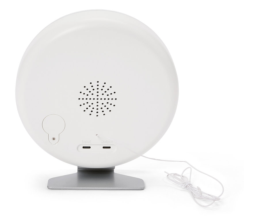 Rückseite einer runden, weißen Lampe auf einem silbernen Sockel mit Lautsprecher, Eingangs- und Ausgangsanschlüssen und einem weißen Kabel.
