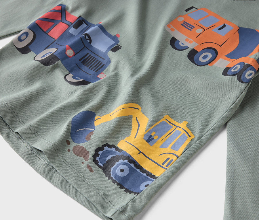 Nahaufnahme eines hellgrünen, langärmeligen Hemdes mit aufgedruckten Bauwagen.